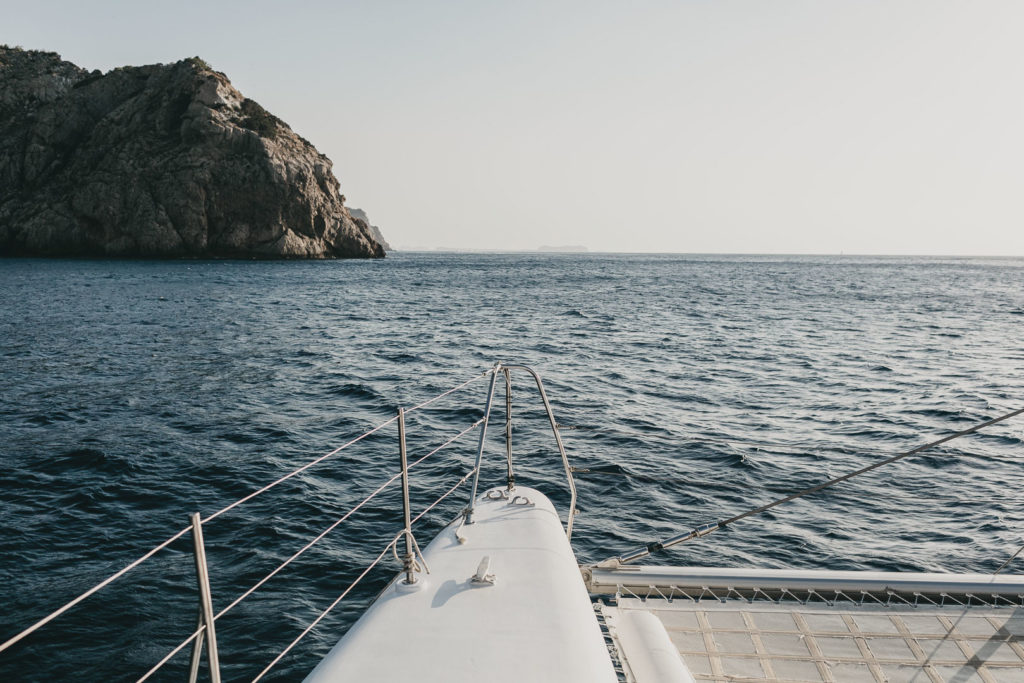 imagen profesional publicitaria del exterior de un catamaran para pasajeros navegando en las aguas de ibiza al atardecer