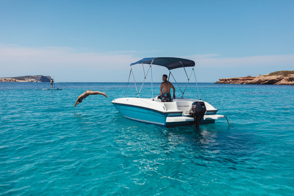 Persona saltando al mar desde una lancha en aguas turquesas de Ibiza