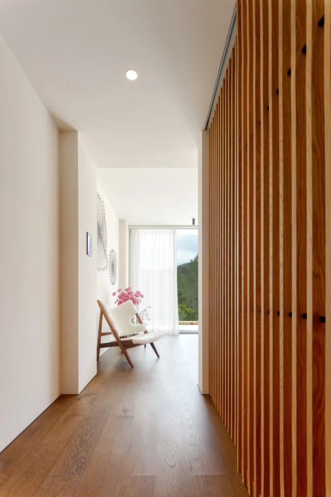 Pasillo de villa en Ibiza con suelo de madera y separación de listones junto al dormitorio